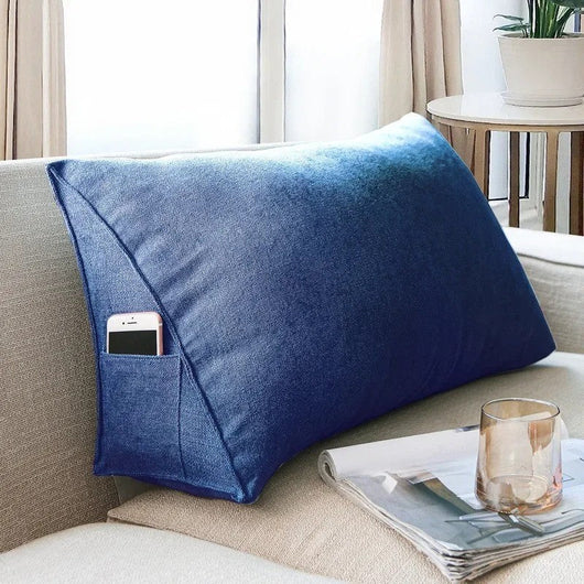 Blue Headboard Pillow Wedge with side pocket holding a phone on beige couch near table