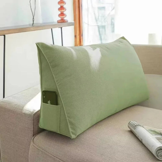 Green fabric Headboard Pillow Wedge with side pocket on beige couch holding a smartphone