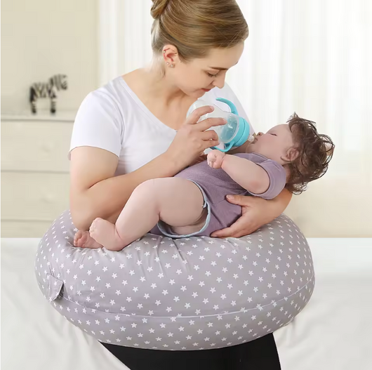 Mother using a pregnancy pillow for breastfeeding while bottle feeding a baby in a star-patterned cover
